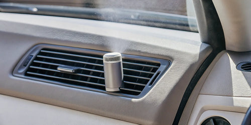 A car air freshener vent clip properly installed on a dashboard air vent.