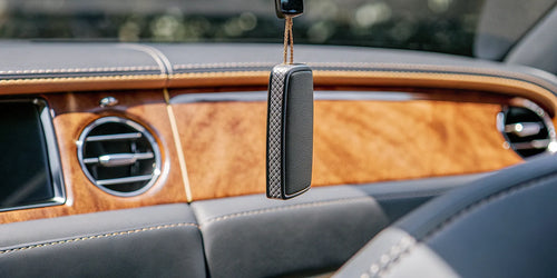 A car fragrance from a subscription service hanging from a rearview mirror.