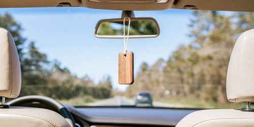 Modern wood car air freshener hanging in a car interior.