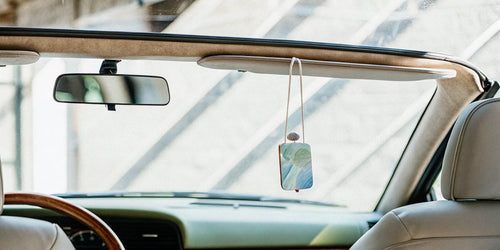 A natural, phthalate-free car air freshener hanging from a rearview mirror.
