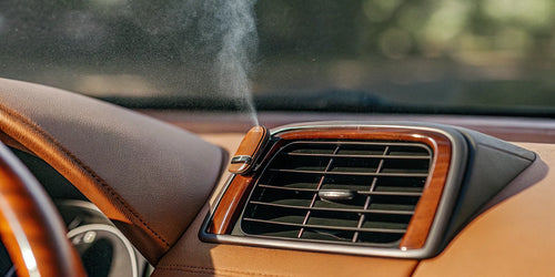 Liquid car air freshener refill clipped to a car's air vent.