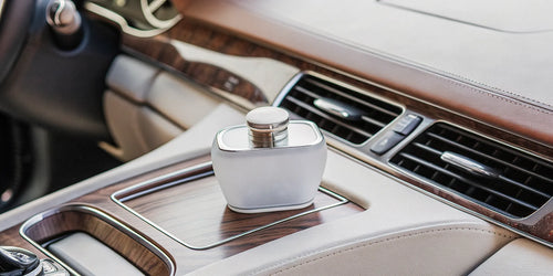 A luxury car perfume diffuser on the wood console of a premium car interior.