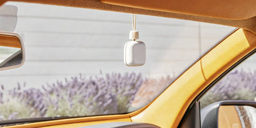 Refillable car air freshener hanging from a car's rearview mirror.