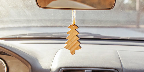 A minimalist wooden car air freshener hanging from a rearview mirror.